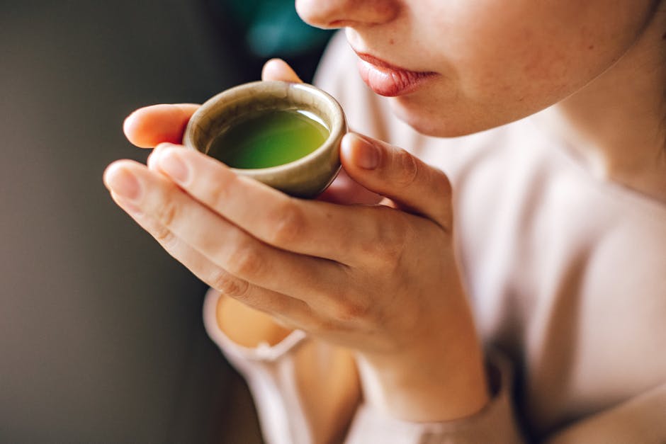 Close-up of a woman enjoying a hot matcha tea, highlighting a healthy lifestyle.