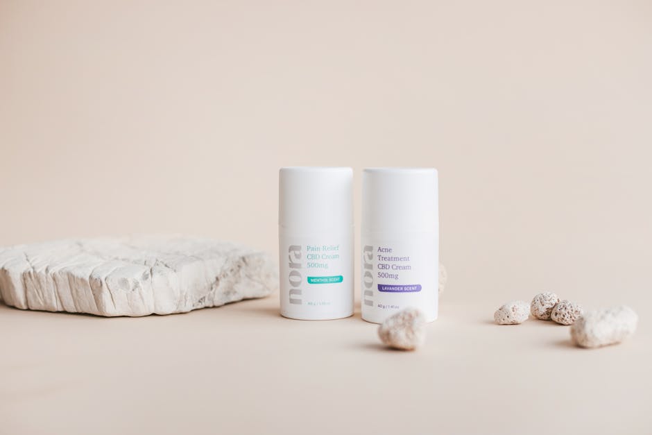 Elegant studio shot of CBD creams with natural stones on beige background, perfect for skincare branding.