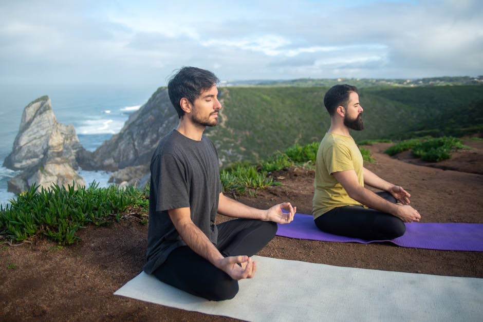 Two men practicing meditation on yoga mats overlooking a scenic cliff in Portugal.