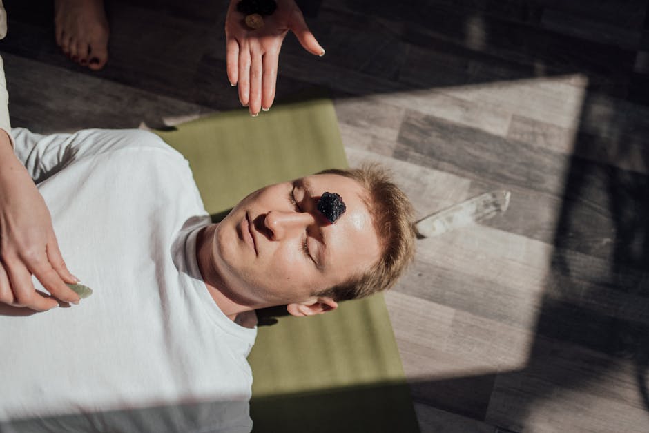 Man lying down with healing crystals for a relaxation therapy session indoors.