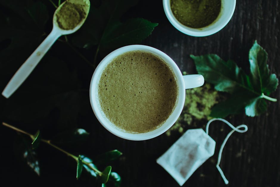 A calming overhead shot of a matcha latte surrounded by leaves and matcha powder for a natural touch.