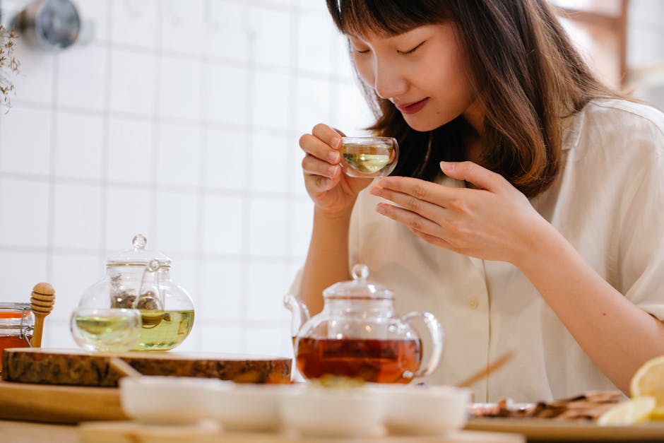A woman savoring a cup of aromatic herbal tea in a cozy indoor kitchen setting.