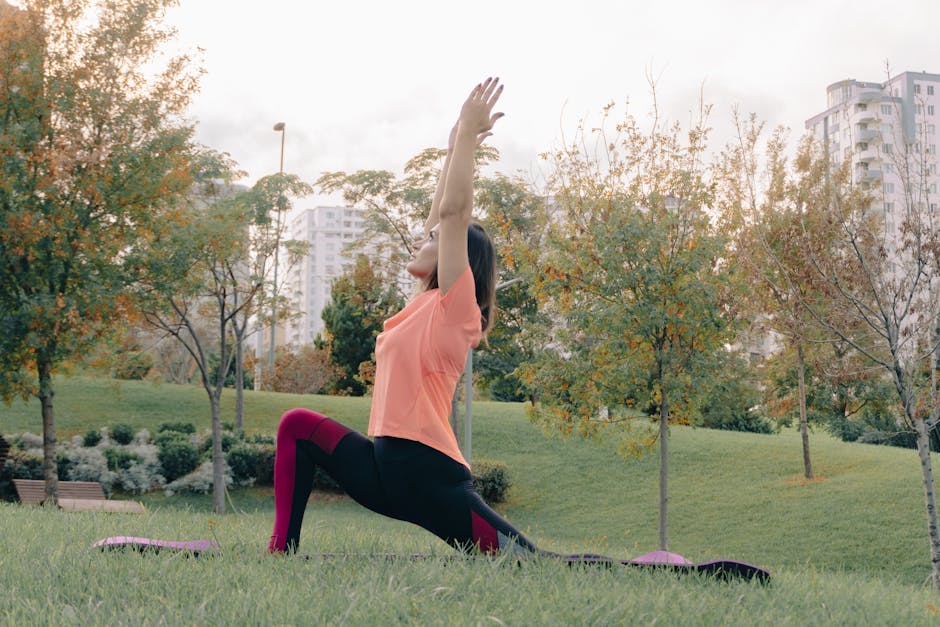 Woman in activewear performing yoga lunge pose in a vibrant green city park.
