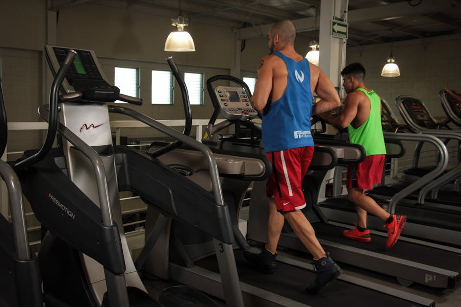 Two men running on treadmills in a modern gym, promoting fitness and health.