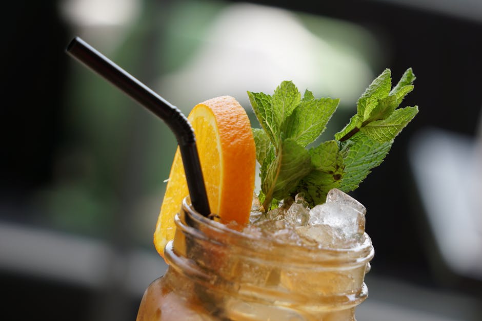 Close-up of a refreshing iced tea with orange slice and mint leaves, perfect for a hot day.