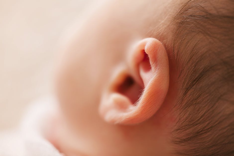 Gentle close-up of a newborn baby's ear, showcasing delicate features in a soft focus image.