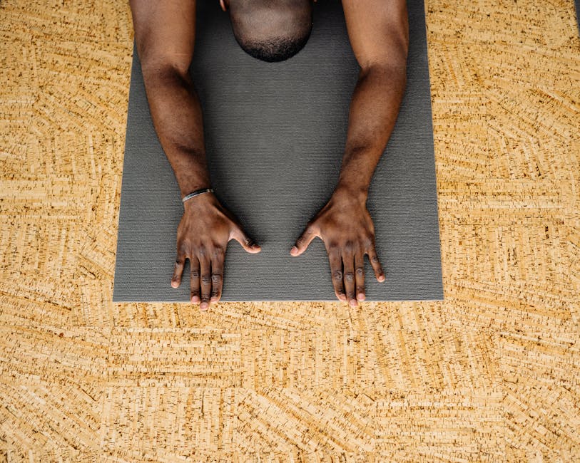 A man in a yoga pose on a mat within an indoor studio, focusing on relaxation.