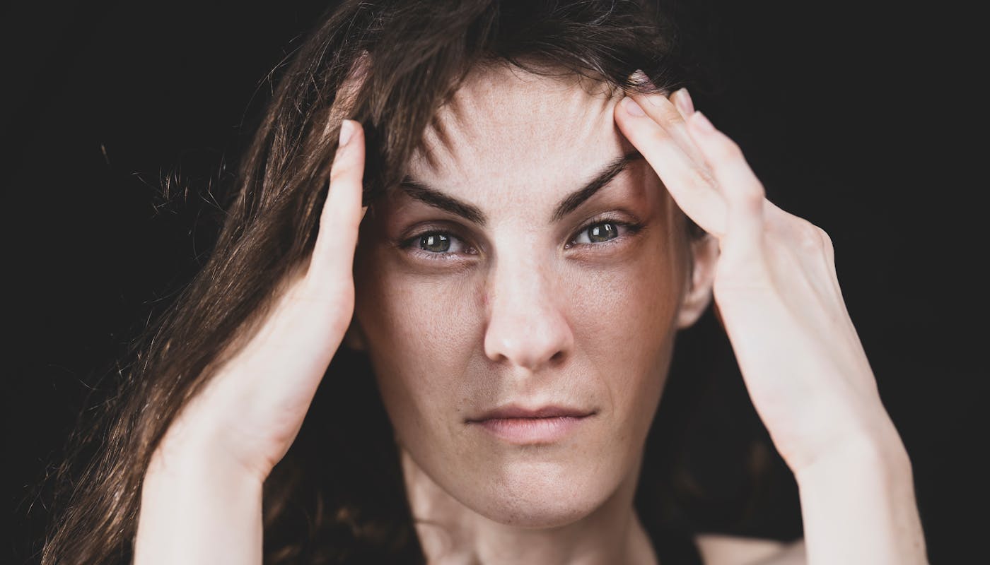 Woman holding her head experiencing stress and anxiety - NAC may help reduce overthinking and rumination