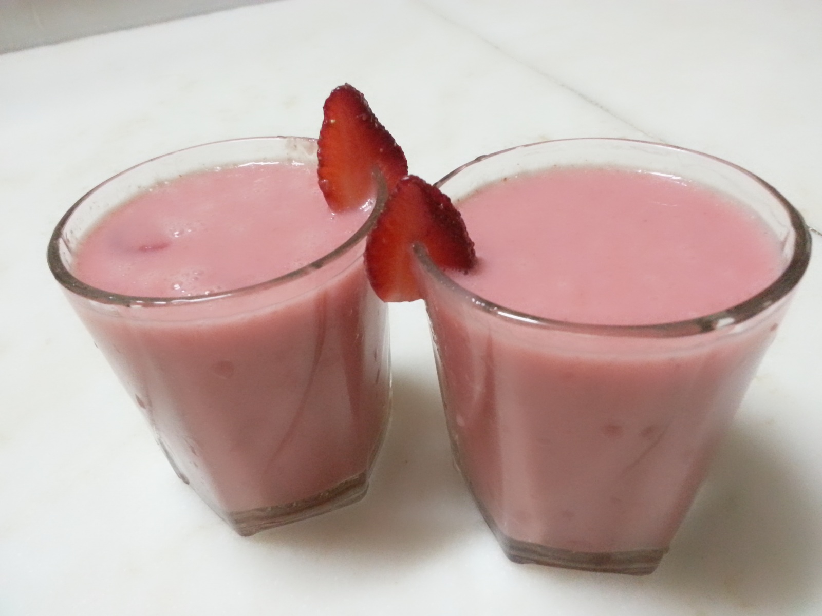 Strawberry smoothie in a glass with fresh fruit